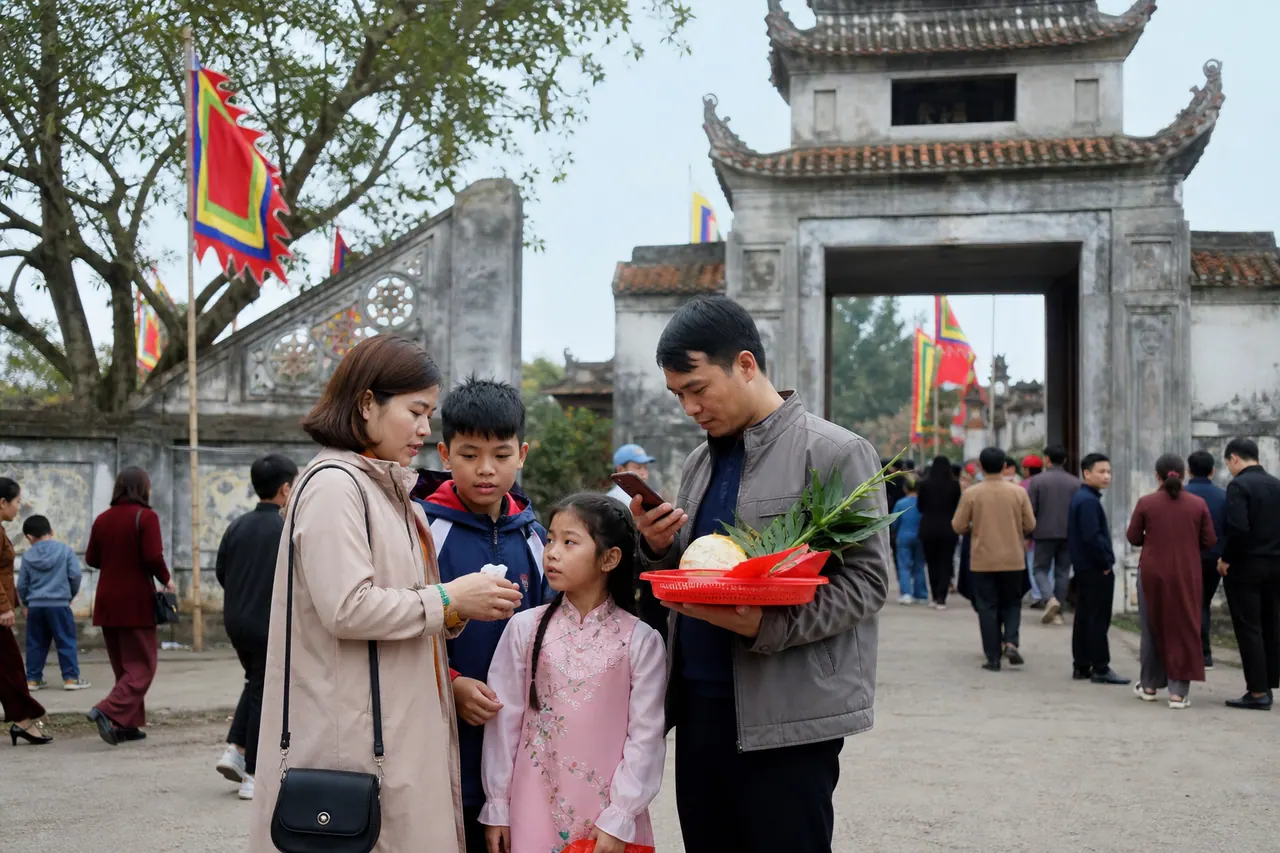 Gia đình đứng gần cổng ngoài của đình làng, kiểm lại đồ đạc và xác nhận điểm hẹn sau khi đi qua khu đông