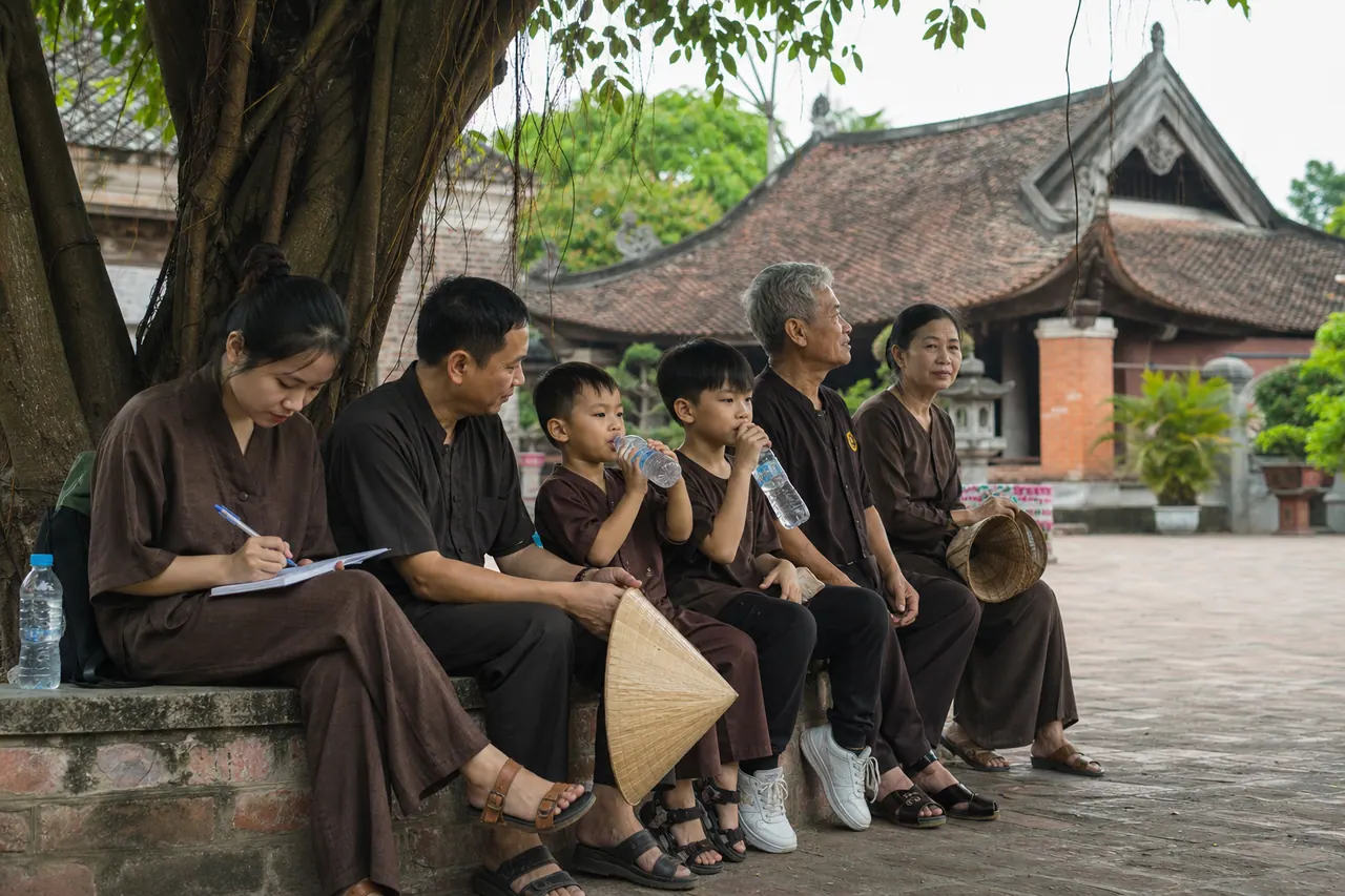 Gia đình ngồi nghỉ thong thả dưới tán cây cổ thụ trong sân Chùa Dâu sau khi hành lễ trang nghiêm