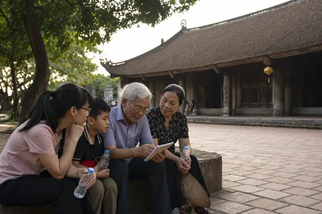 Bốn người cùng xem cuốn sổ khi ngồi nghỉ cạnh sân lát gạch