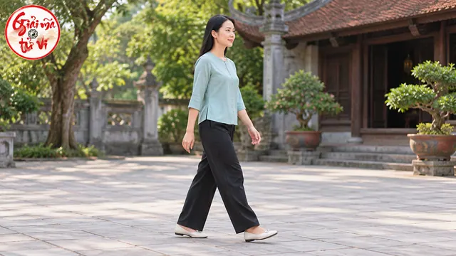 Người nữ áo xanh nhạt và quần sẫm đi trong sân, hai tay nhìn rõ và logo Giải Mã Tử Vi ở góc trên trái