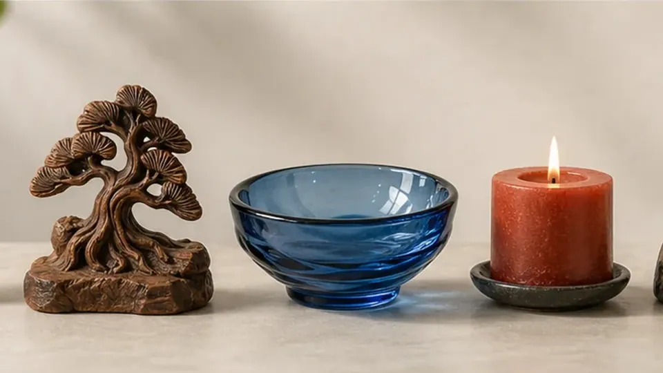Cây trang trí, chén thủy tinh xanh và nến đỏ đang cháy đặt cạnh nhau