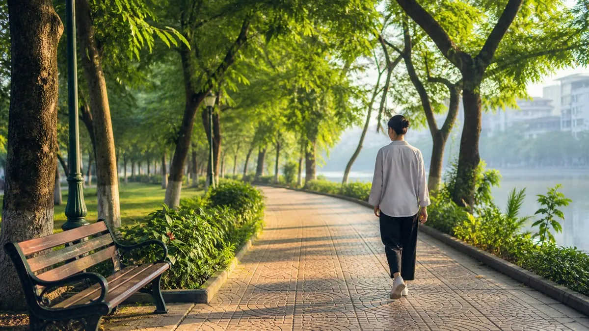 Một người đi bộ trên lối lát gạch ven hồ có cây và ghế