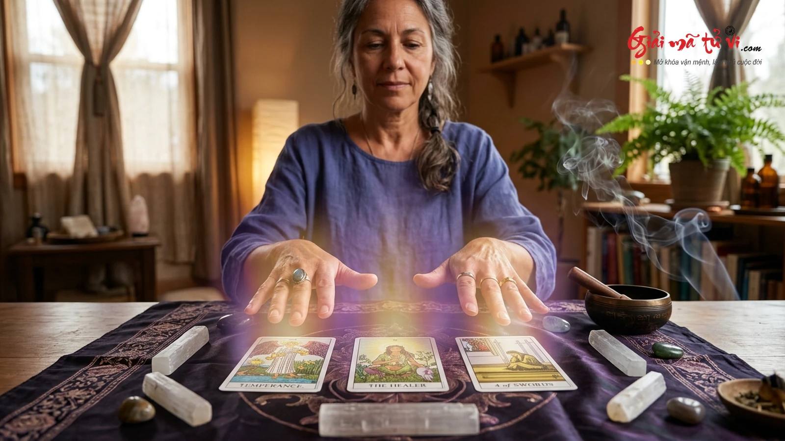 Kỹ Thuật Quét Năng Lượng Trường Sinh Học Trong Medical Tarot – Đôi bàn tay của Reader tỏa ra ánh sáng hào quang vàng tím nhẹ nhàng trên các lá bài Temperance, The Healer, 4 of Swords, chuông xoay Tây Tạng và thạch anh trắng
