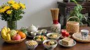 Bình cúc vàng, giỏ trái cây, chén trà và các món rau, đậu trên bàn gỗ